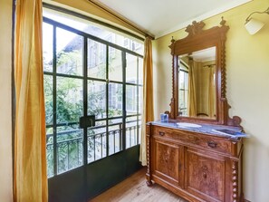 A room with a large window, a wooden dresser, and a mirror. - Belvilla by OYO Fienile (Portacomaro)