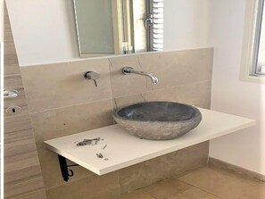 A bathroom with a stone sink, a mirror, and a towel rack.