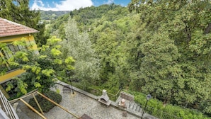 A courtyard with stone flooring, benches, and a view of a forested hillside. - Apartment in Portacomaro With Garden (Portacomaro)