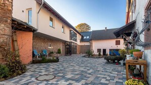 A courtyard with a checkered tile floor, stone walls, and a wooden bench. - Snug Apartment in Birresborn With Garden (Birresborn)