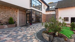 A modern house with a spacious patio, stone walls, and a well-maintained garden. - Snug Apartment in Birresborn With Garden (Birresborn)