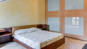 Ein Schlafzimmer mit einem Bett, einem Holzkopfende, Nachttischen und einer Schiebetür aus Glas.