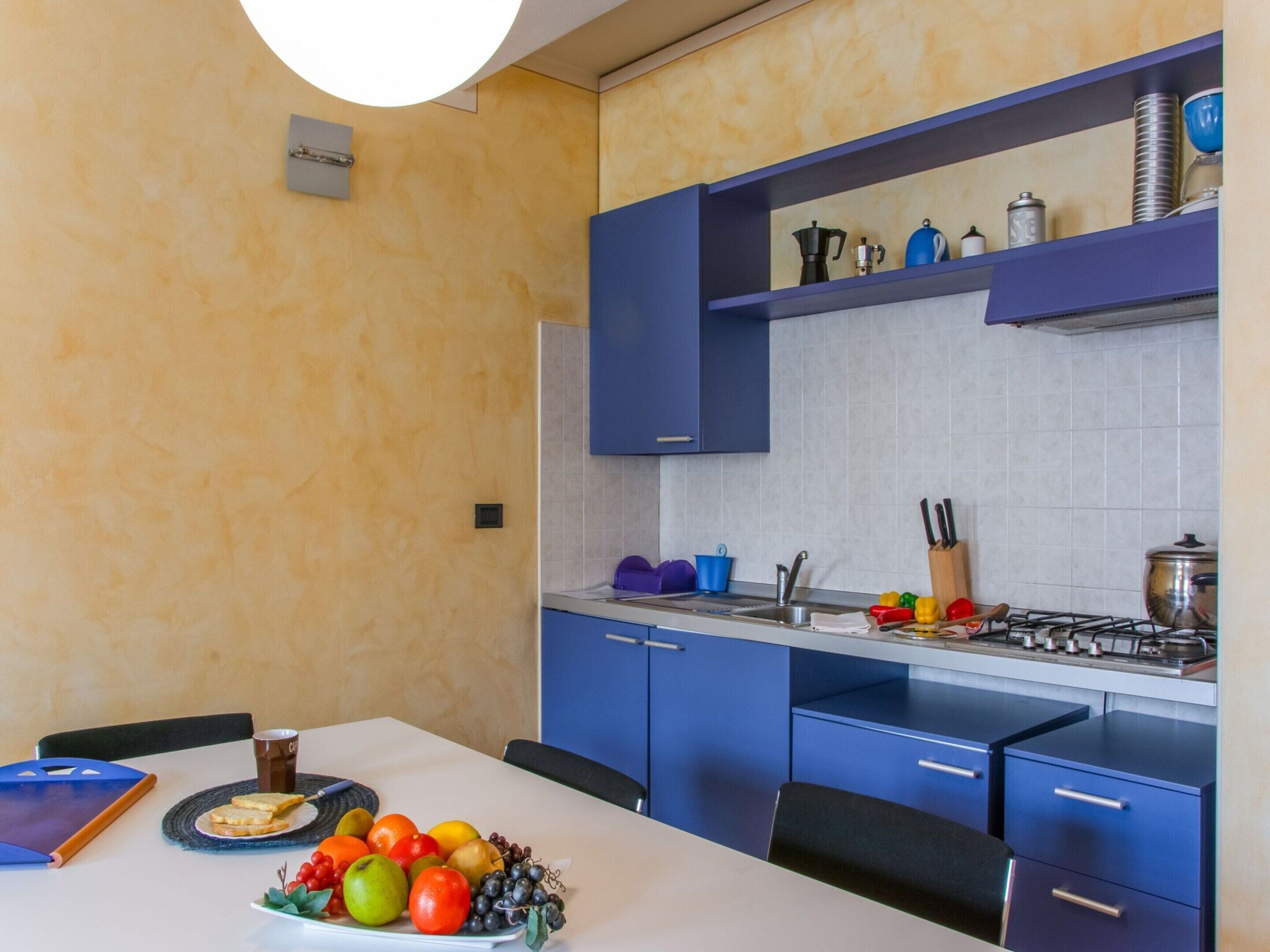 A modern kitchen with blue cabinets, a gas stove, and a dining area with a table set for two.