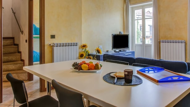 Ein Essbereich mit einem Tisch für zwei Personen, einem Fernsehgerät auf einem Schrank und einer Couch.