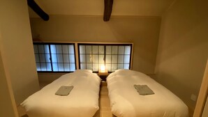 A room with two single beds, a nightstand with a lamp, and a traditional Japanese shoji screen behind the beds. - Campton Higashiyama Roku (Kyoto)