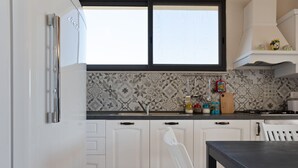 Una cocina con armarios blancos, encimera negra y ventana sobre el fregadero.