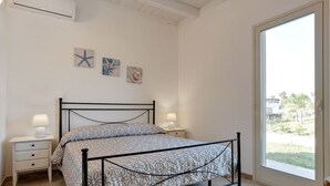 Un dormitorio con una cama, dos mesitas de noche, un ventanal y obras de arte en la pared.
