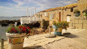 Un paseo marítimo con edificios de piedra, plantas en macetas y vistas al mar.