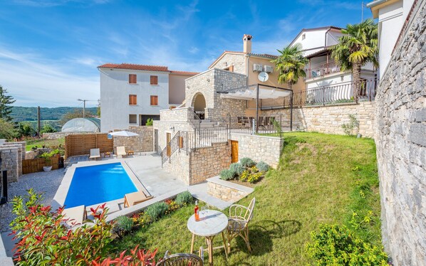 A villa with a swimming pool, outdoor seating, and a stone facade. - Holiday Home Pazin With Scenic Pool (Pazin)