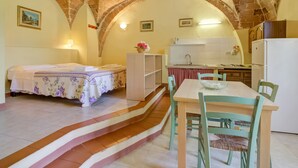 A cozy room with a bed, a dining table, and a kitchen area. - Tuscan Farmhouse in Montescudaio near Sea (Montescudaio)