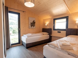 Una habitación con dos camas, paredes de madera, una ventana con vistas y un cuadro en la pared.