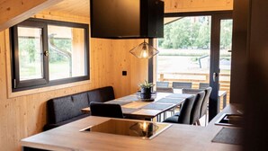 Eine moderne Küche mit einer zentralen Kochinsel, Holzwänden und großen Fenstern.