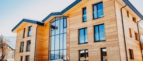 A modern wooden building with large windows and a sloped roof.
