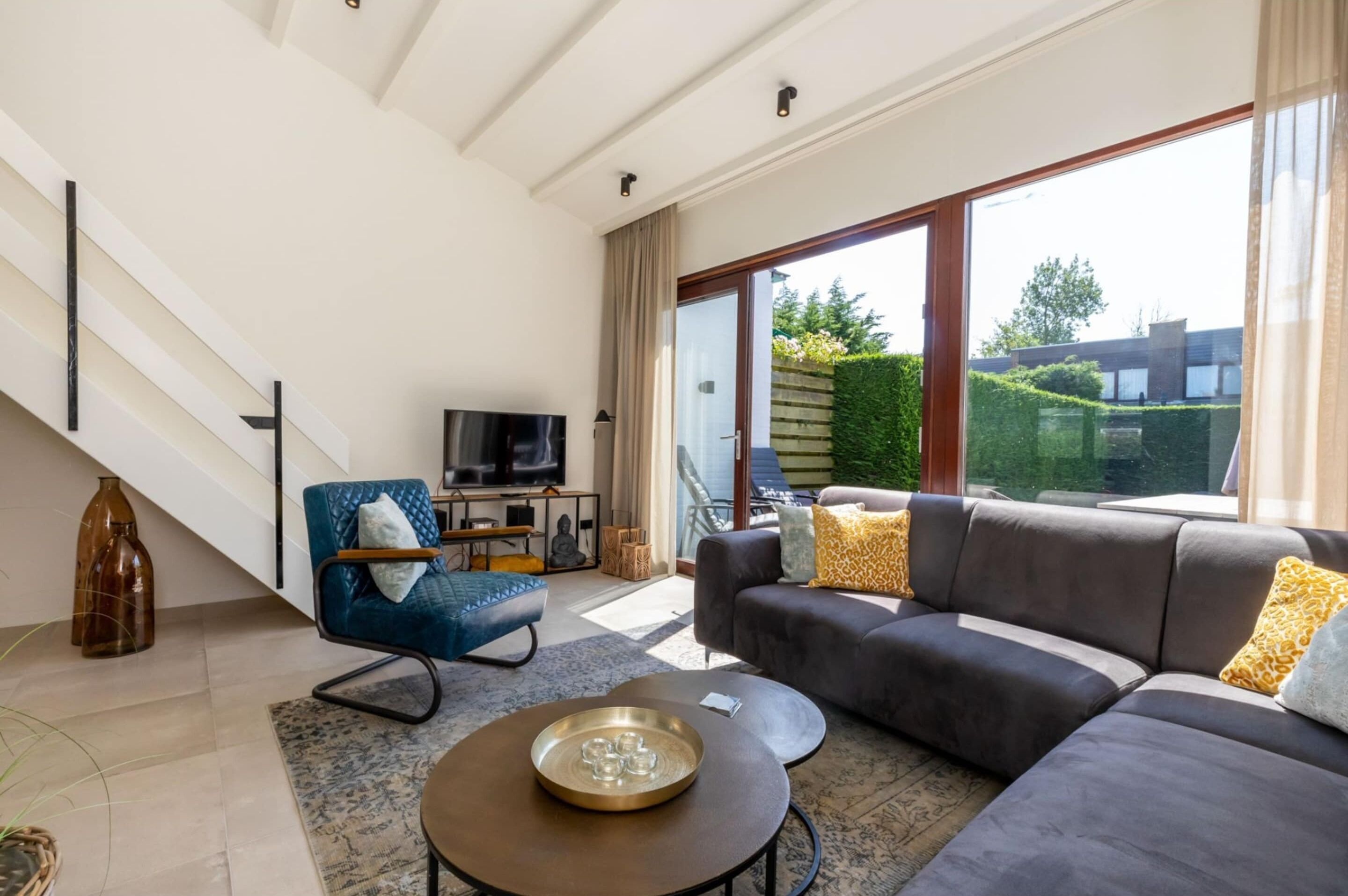 A modern living room with a grey sofa, blue armchair, and a flat-screen TV.