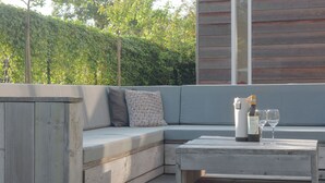 A modern outdoor seating area with a wooden bench and a cushioned sofa. - Family Home Near Sea & Dunes (Noordwijk)