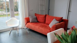 A modern living room with a red sofa, white chair, and a wooden dining table. - Family Home Near Sea & Dunes (Noordwijk)