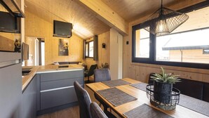 A modern kitchen with wooden cabinetry, a built-in stove, and a dining area with a wooden table and chairs. - Apartment With Balcony (Sankt Georgen am Kreischberg)