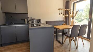 A modern kitchen with a central island, built-in appliances, and a dining area with a wooden table and chairs.