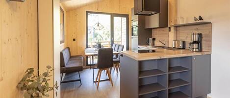 A modern kitchen with a central island, wooden flooring, and a view to an outdoor area.