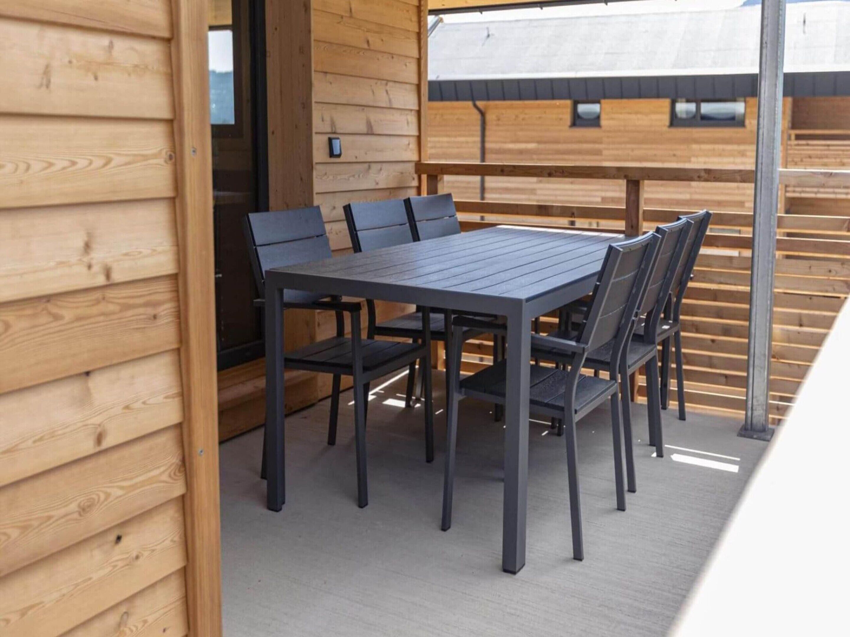 Une terrasse extérieure en bois, avec une table et des chaises.