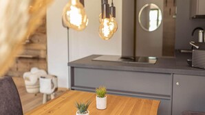 A modern kitchen with pendant lighting, a wooden dining table, and potted plants. - Apartment With Balcony (Sankt Georgen am Kreischberg)