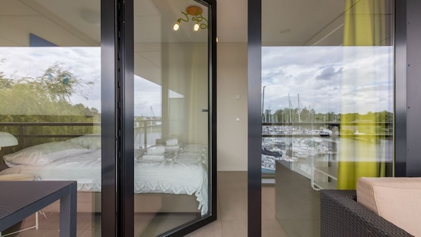 A modern room with a glass door leading to a balcony with a marina view. - Holiday Apartment in a Prime Location on the Veerse Lake (Arnemuiden)