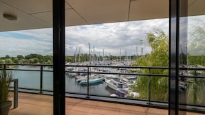 A view from a balcony overlooking a marina with boats docked, a calm body of water, and a cloudy sky. - Holiday Apartment in a Prime Location on the Veerse Lake (Arnemuiden)