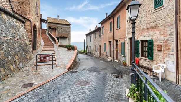A narrow cobblestone street flanked by historic stone buildings with traditional shutters and a staircase leading to a building with a tiled roof. - Holiday Home in Ficulle With Pool Access (Ficulle)