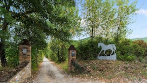 A gravel path leading to a gate with a horse sculpture and a sign. - Holiday Home in Ficulle With Pool Access (Ficulle)