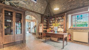 A rustic library with stone walls, wooden bookshelves, and a table with a vase. - Holiday Home in Ficulle With Pool Access (Ficulle)