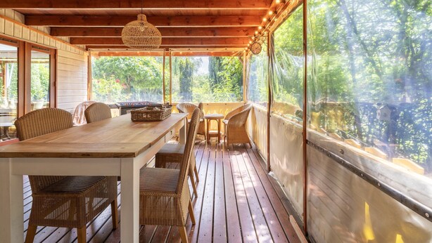 A covered outdoor dining area with wooden furniture and a view of the surrounding greenery. - Pleasing Chalet in Stegeren near Forest (Stegeren)