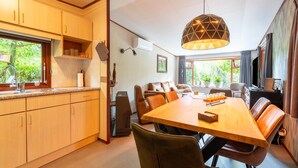 A modern kitchen with wooden cabinets and a dining area with a large table and leather chairs. - Pleasing Chalet in Stegeren near Forest (Stegeren)