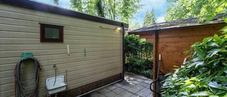 A covered outdoor area with a wooden structure, a hose, and a window.