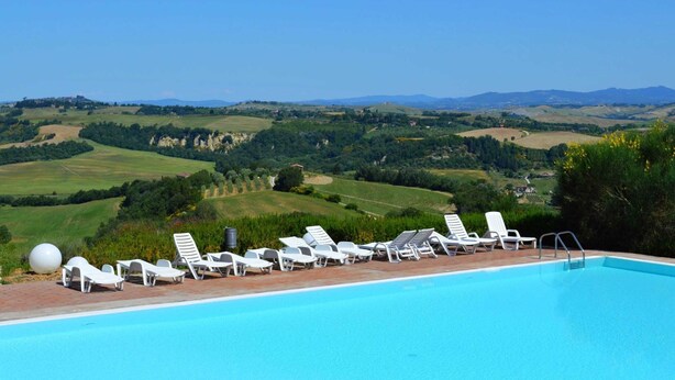 A swimming pool with white lounge chairs and a clear view of rolling hills and distant mountains. - Belvilla by OYO Nando (Asciano)