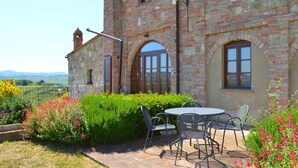 A stone building with a patio area featuring outdoor seating and a view of the countryside. - Belvilla by OYO Nando (Asciano)