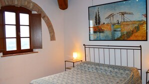 A bedroom with a bed, a window, a painting, and a lamp. - Belvilla by OYO Nando (Asciano)