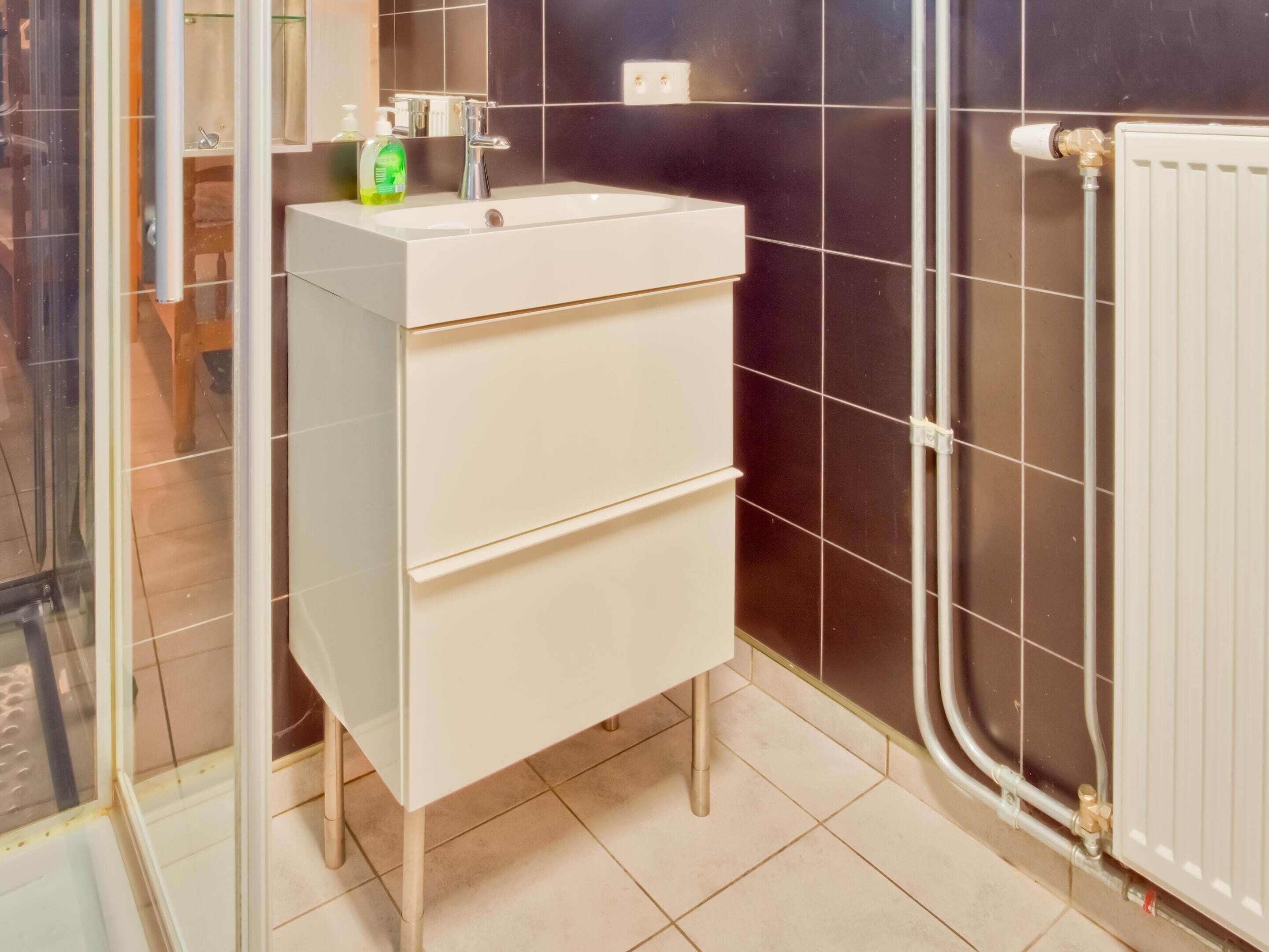 A bathroom with a white sink, a mirror, and a radiator.