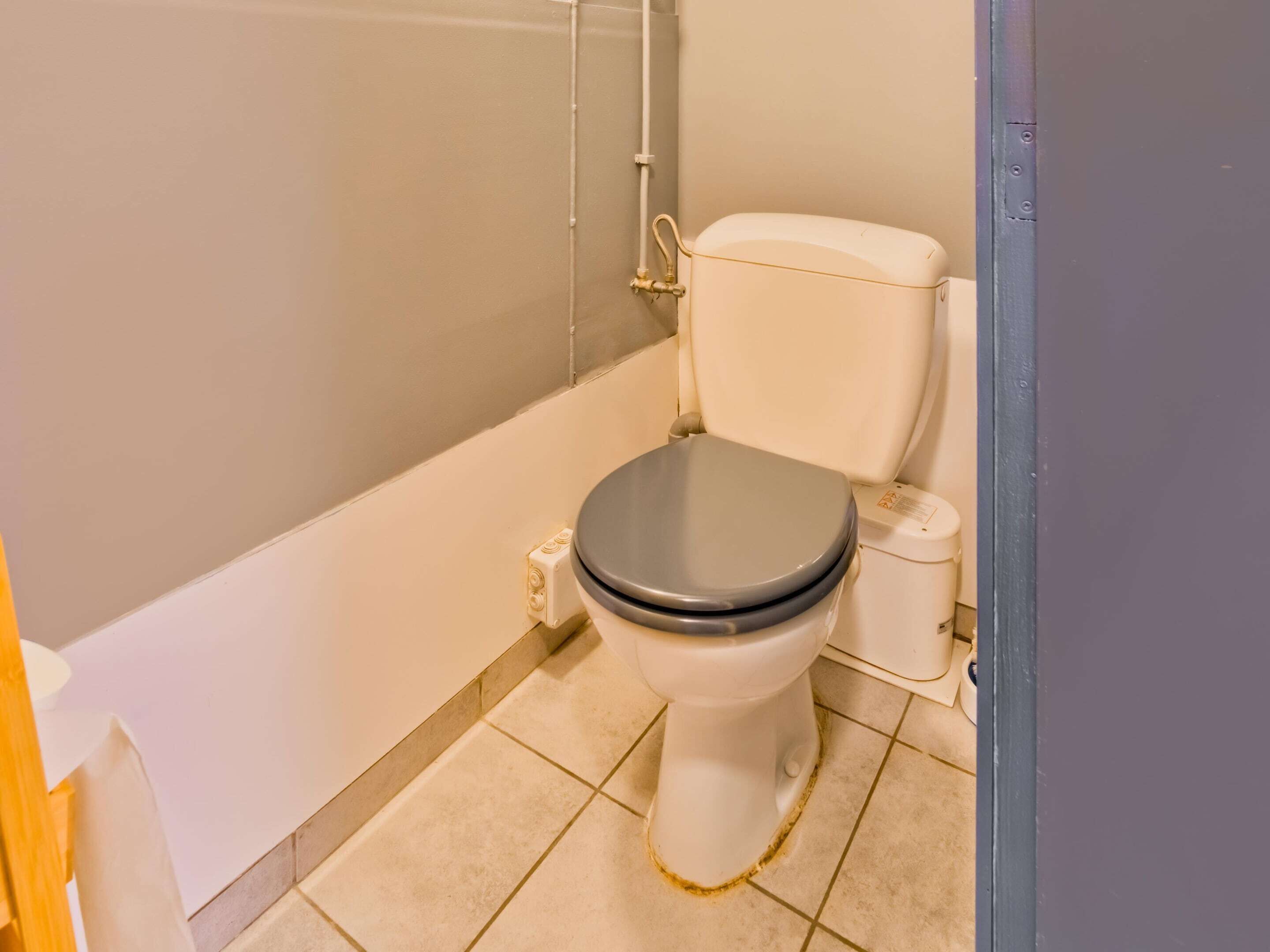 A standard bathroom with a toilet, a shower, and a tiled floor.