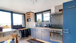 Cocina compacta con vistas, zona de comedor y una mesita.