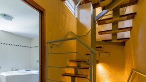 Una escalera de caracol con escalones de madera y barandillas de metal, que conduce a un piso superior.