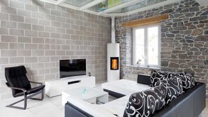 Uma sala de estar moderna com uma parede de pedra, uma lareira e uma televisão.