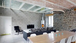 Um interior moderno com parede de pedra, mesa de jantar de madeira e televisão.