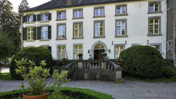 Ein großes, weißes Gebäude mit vielen Fenstern und einem zentralen Eingang.