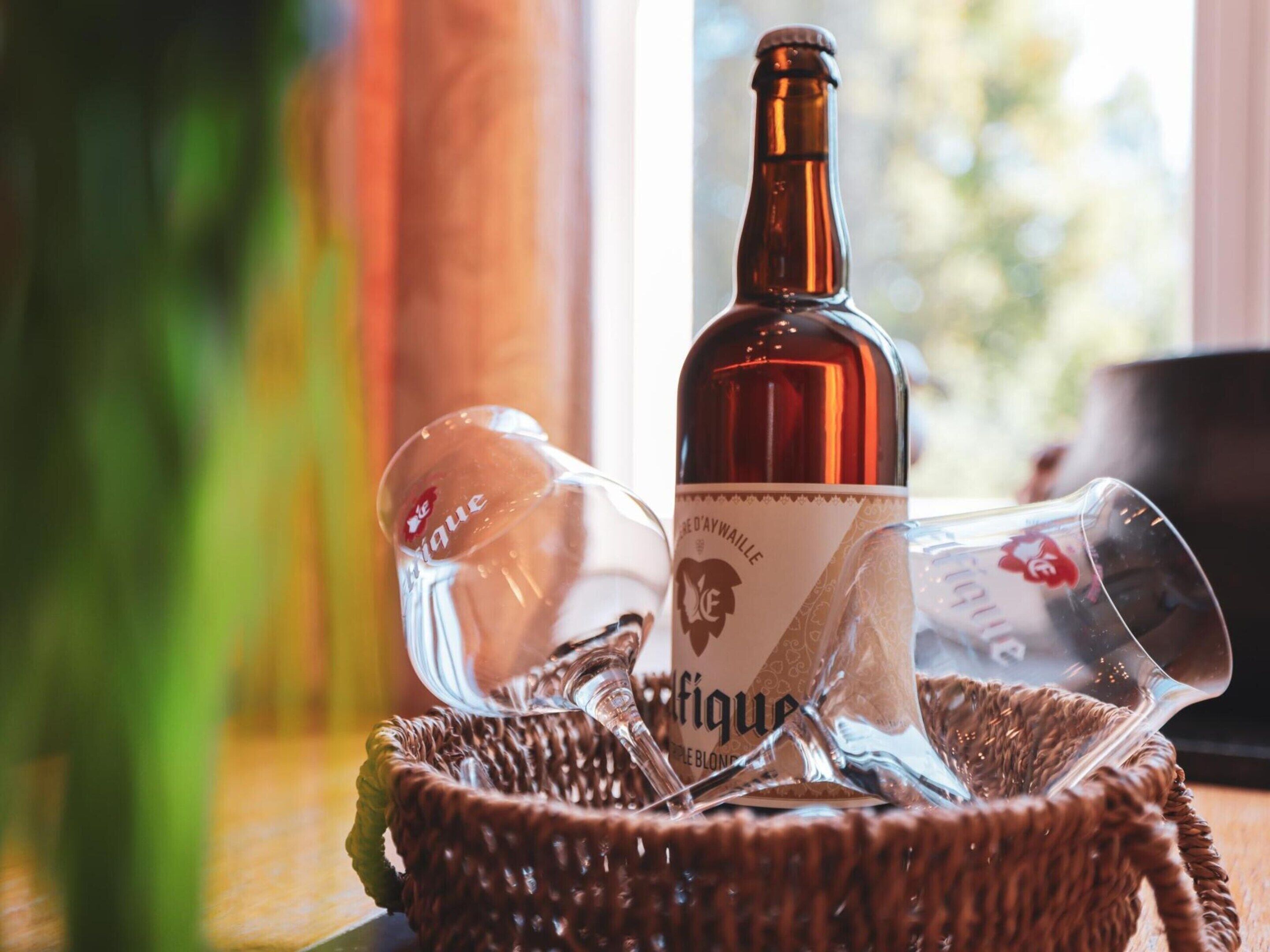 A bottle of wine and two glasses on a woven basket.
