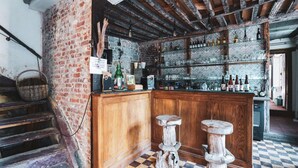 Un coin bar au style rustique, avec un sol à carreaux, un comptoir en bois et des tabourets.