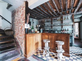 Un área de bar rústica con piso de cuadros, mostrador de madera y taburetes.