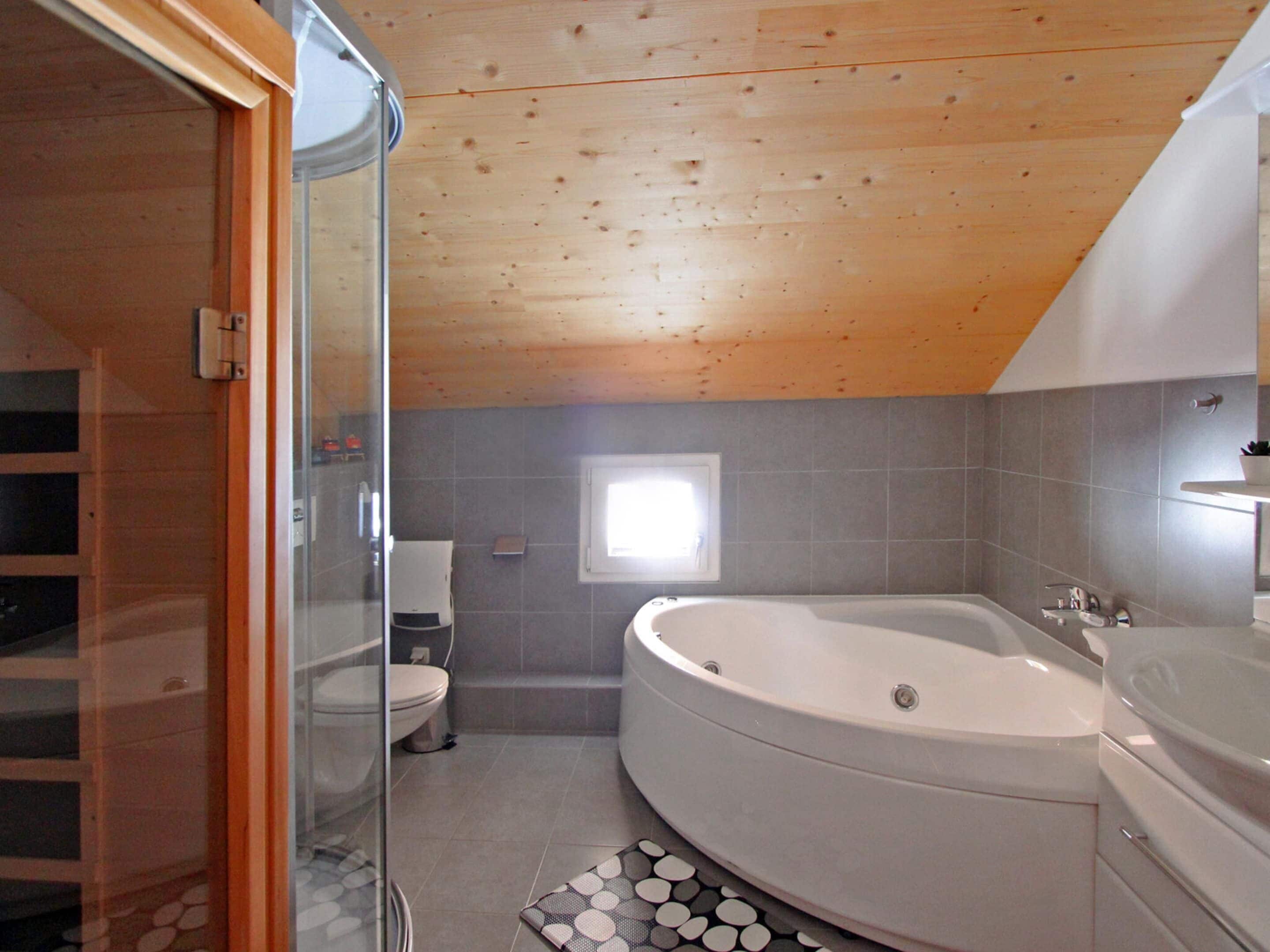 A bathroom with a large bathtub, a toilet, and a glass shower enclosure.