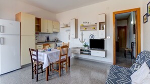 A compact living space with a kitchenette, dining area, and a TV. - Restful Apartment in Cala Gonone with Balcony near Sea Beach (Dorgali)