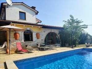 A poolside area with a stone building, a pool, and outdoor furniture. - Holiday Home Sisan Near Beach & Pool (Liznjan)