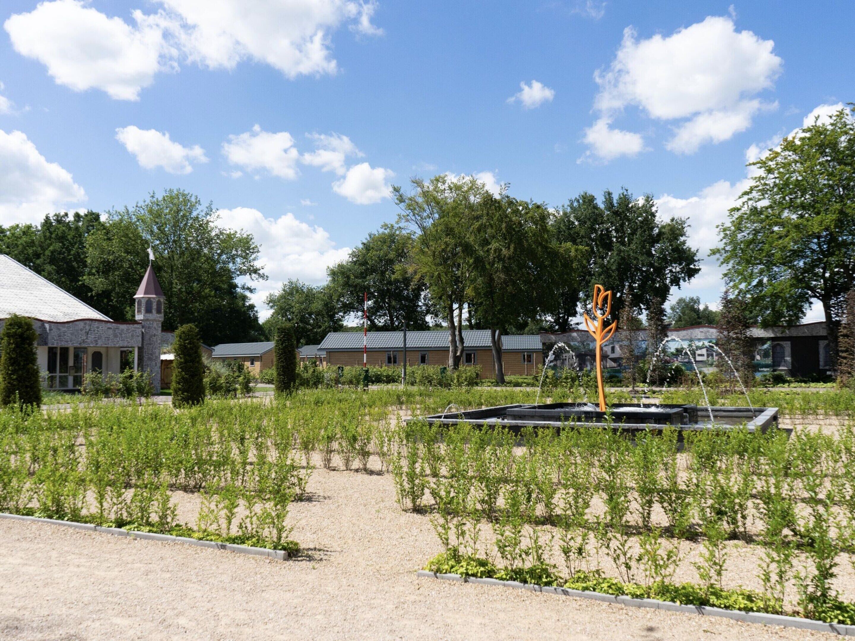 A garden with a fountain, a church, and a building with a tower.